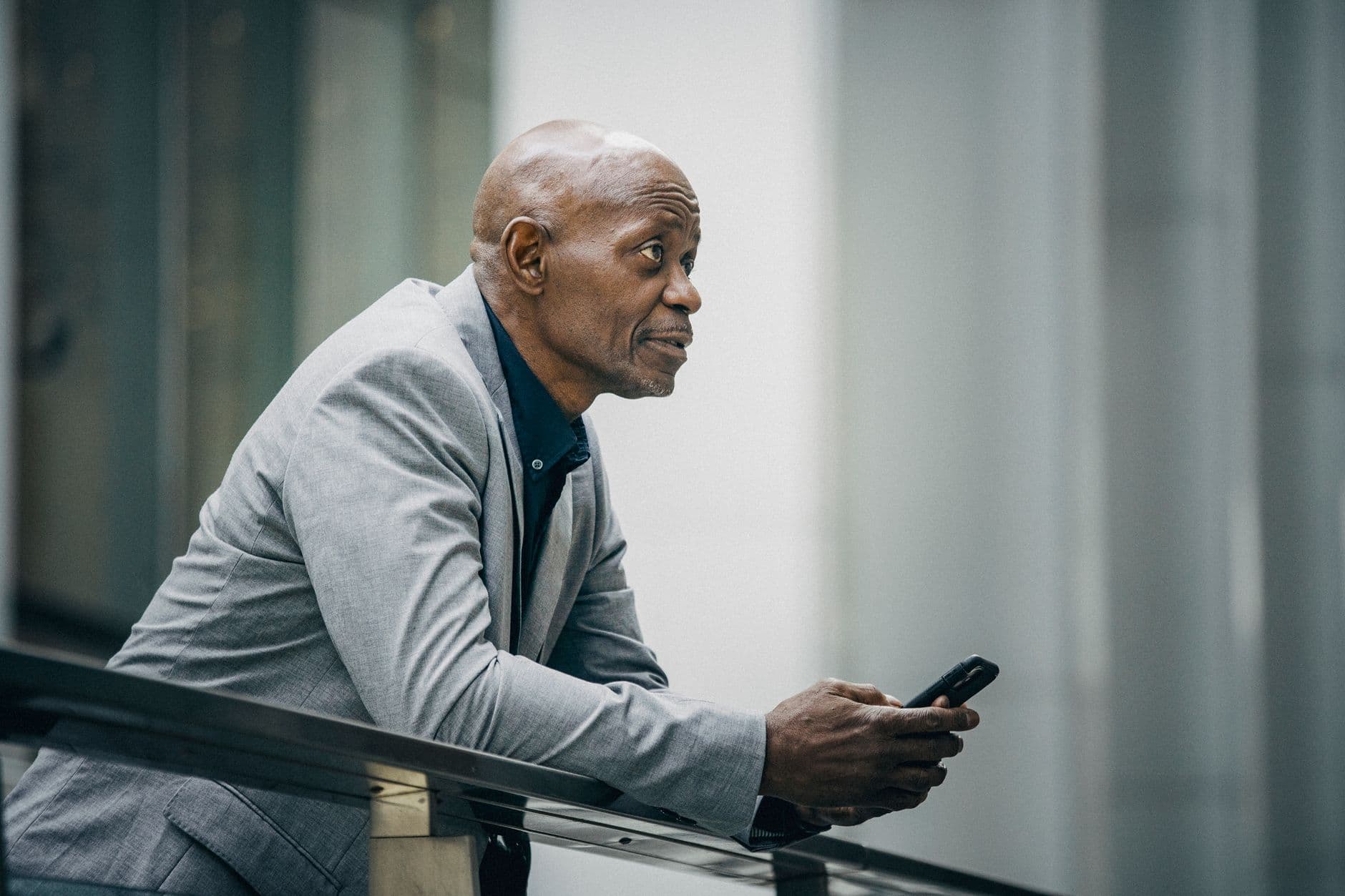 A man staring off, his phone lighting up unnoticed on the desk