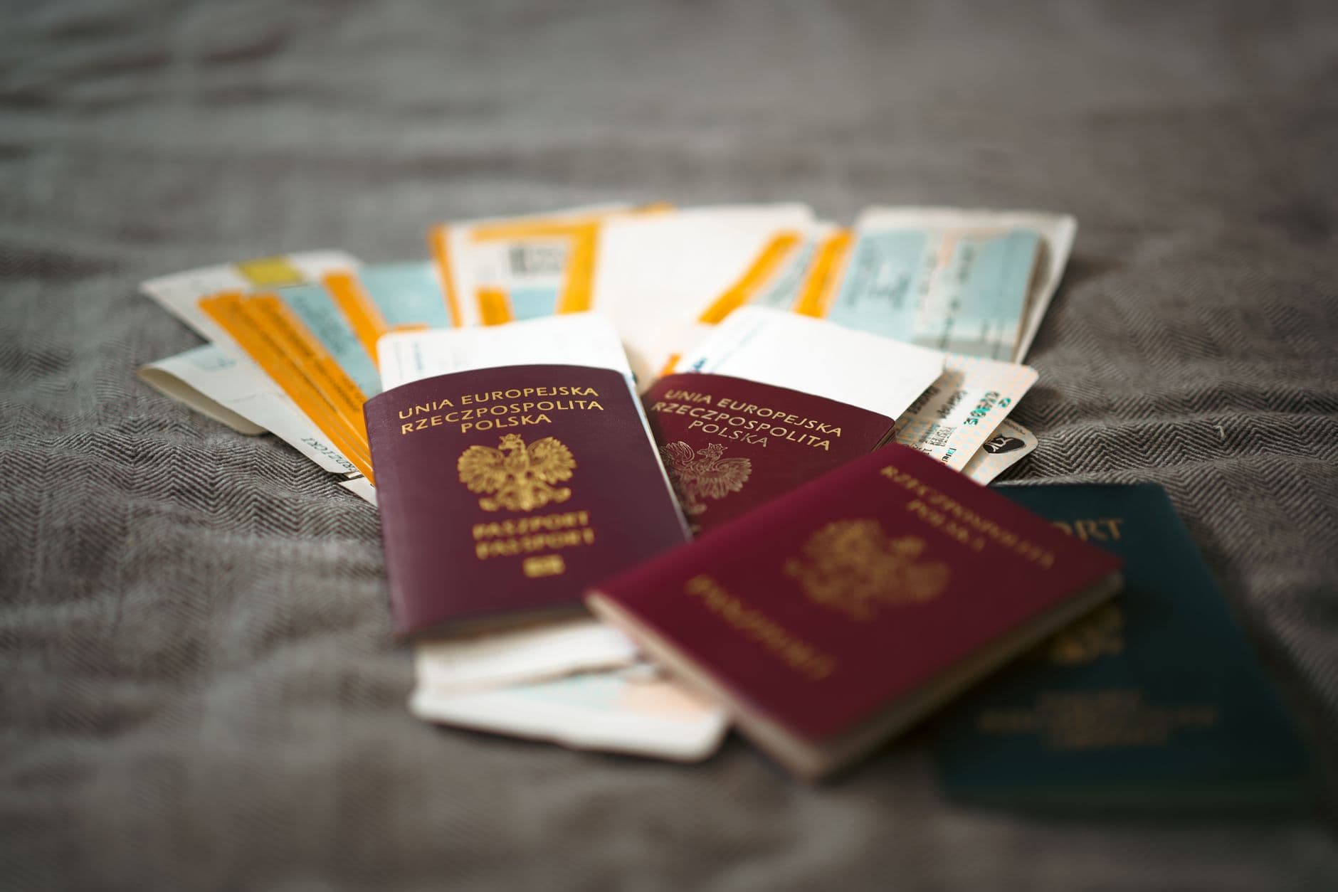 An open suitcase on a bed with a passport and boarding pass