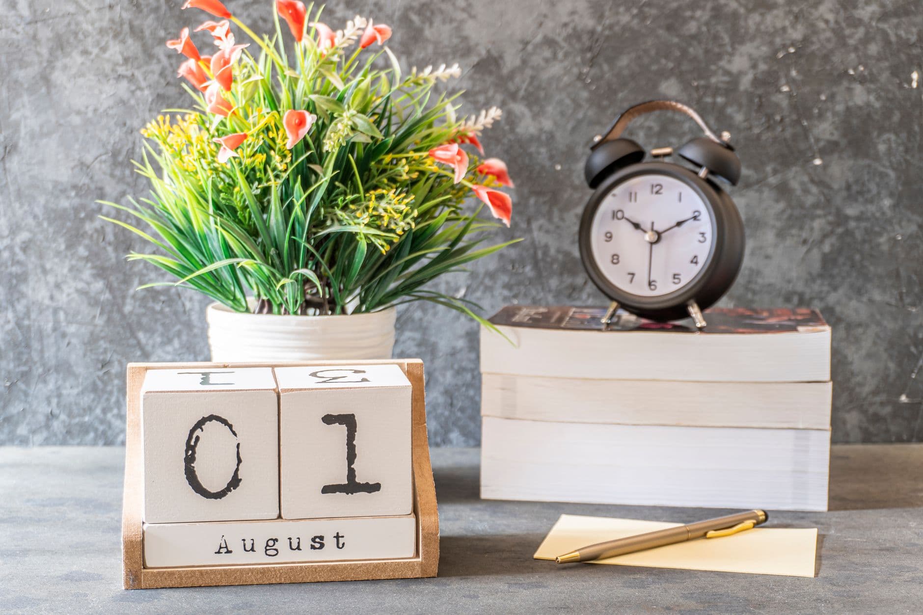A calendar, an alarm clock and a notepad together on a desk