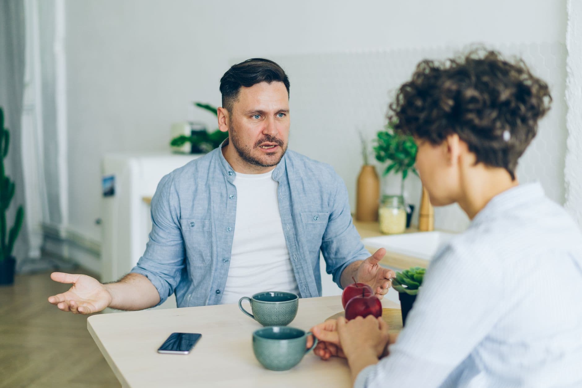 Two people talking across a kitchen table