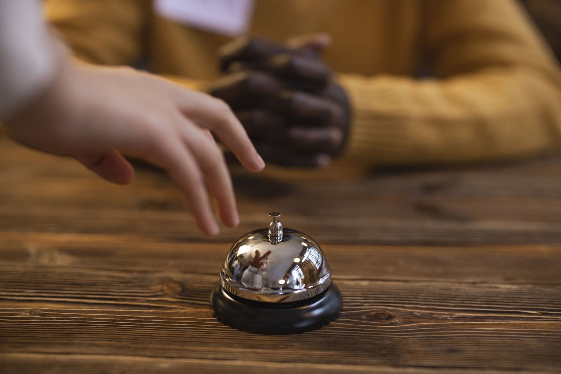 A hand reaching for a ringing iPhone on a bedside table