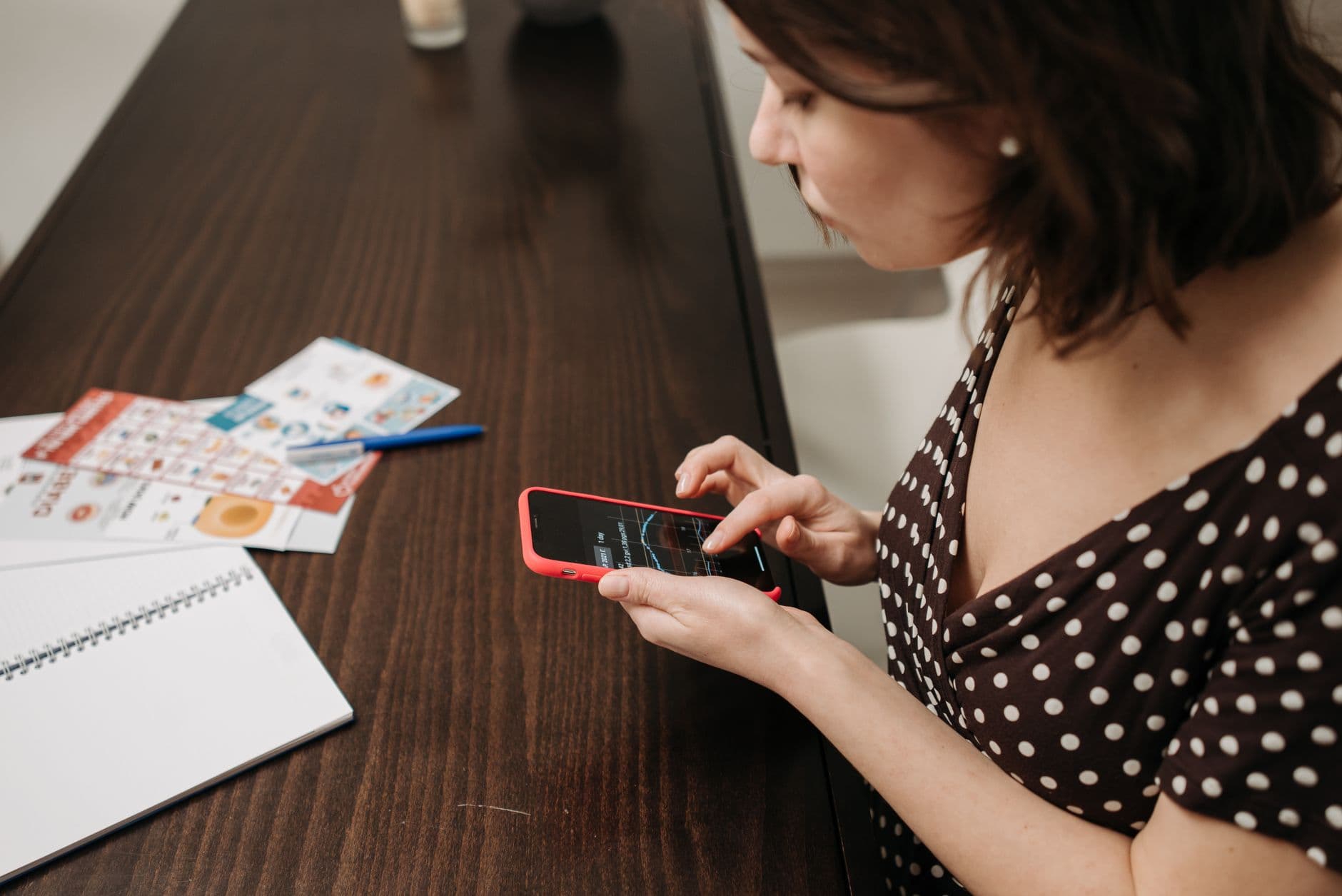 A woman installing an app on her smartphone at a table