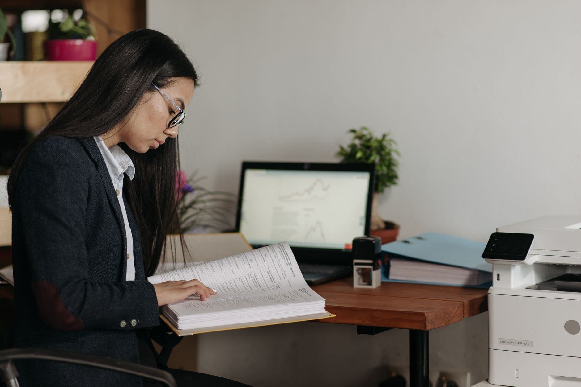 A woman reading a printed document at her desk